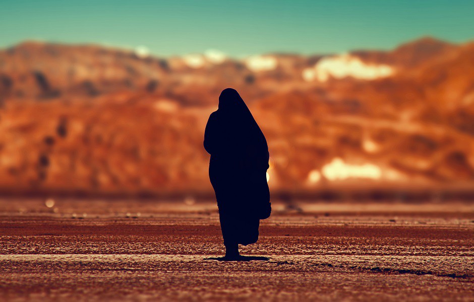 Mujer cubierta por un velo en un desierto de Oriente Medio (Unsplash).